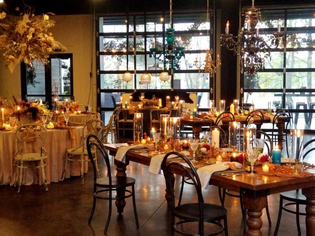 Candlelit autumn event venue with chandeliers and floral arrangements