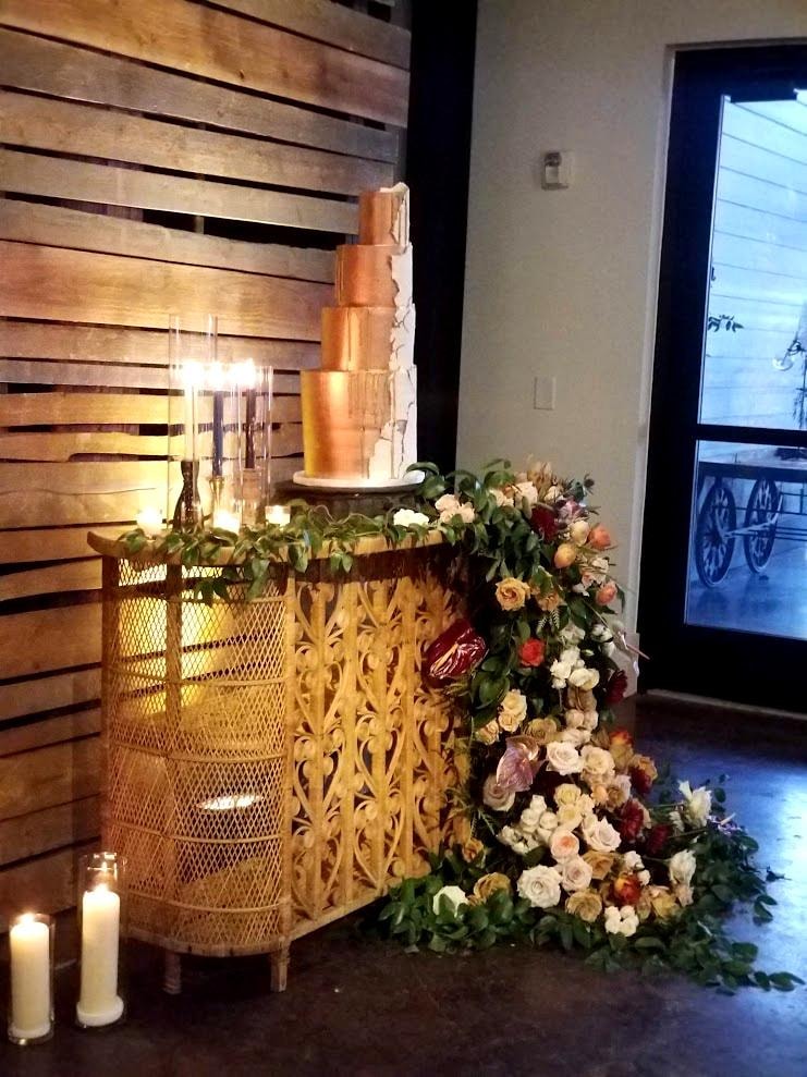 Copper and white tiered wedding cake with lush floral floor arrangement