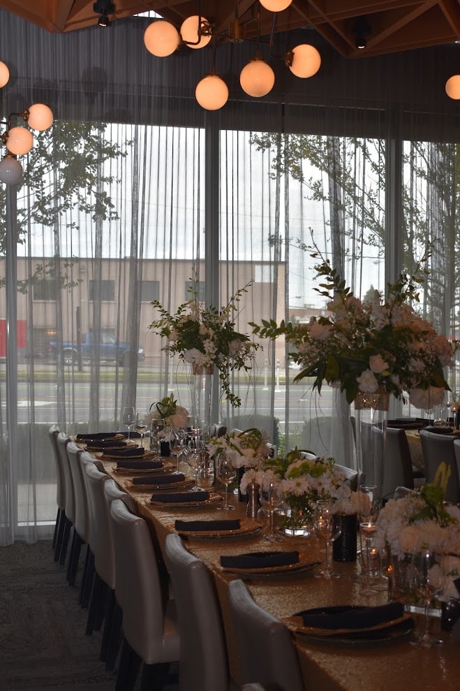 Gold sequin banquet table wide view with white floral arrangements and globe lights
