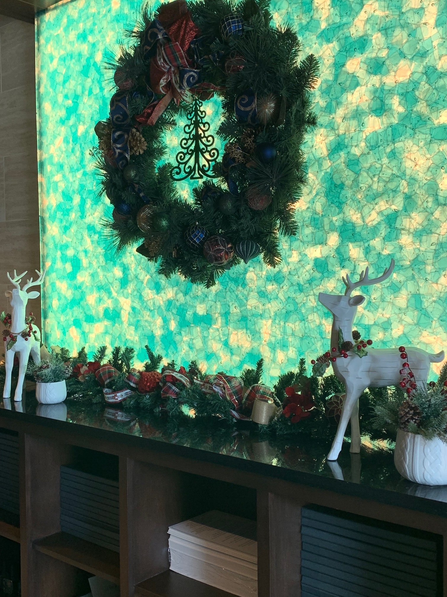 Holiday wreath and white reindeer display against teal mosaic background